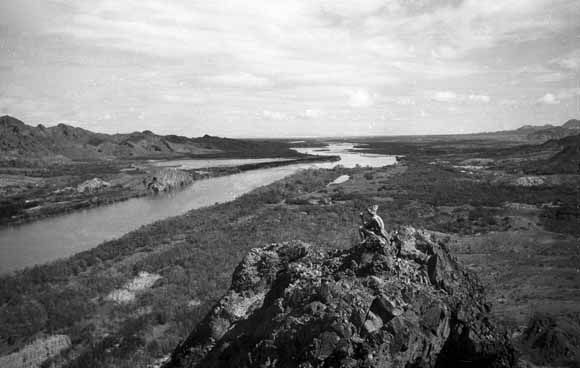 photo of person on spire in middleground and river stretching off into the distance in the background