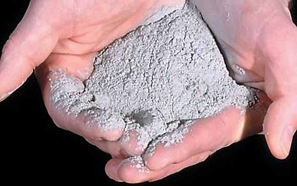 Close-up photograph of person's hands holding half a cup of rock flour