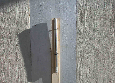 Figure 2. Photograph showing the 2-inch-diameter steel casing of a traditional crest-stage gage in which a transducer is installed. The gage is attached to a wooden lath and secured with nylon ties.