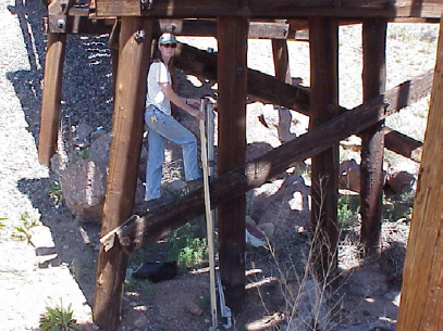 Figure 5. Photograph showing USGS hydrologist attaching an absolute pressure transducer to a bridge piling at Arroyo Hondo near Santa Fe, N. Mex.