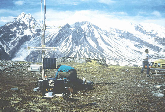 Photo of USGS volcano seismologist servicing a seismic station.