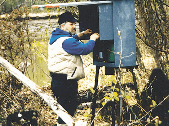 Photo of USGS hydrologist servicing stram-gaging equipment.