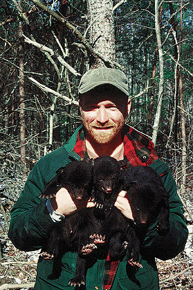 Photo showing a man holding a bear cub.