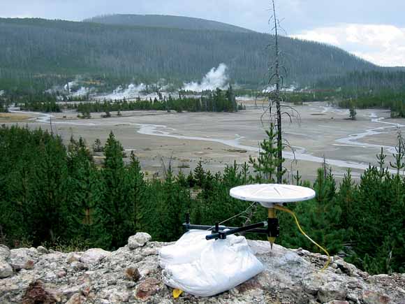 photograph of GPS station on hill overlooking geyser basin