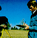 A color photograph of a man holding a notebook for a field survey.