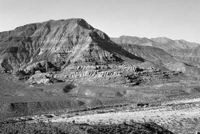 Photograph of steep hillside with nearly flat-lying strata exposed and dry wash in the foreground