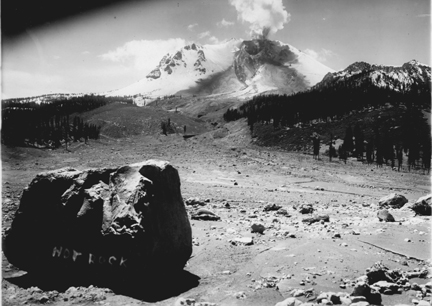 Photograph of Lassen Peak by B.F. Loomis taken on the morning of May 22, 1915, before the climatic eruption of the day, shows a lava flow from the summit and the path of the avalanche and debris flows of May 19-20.  Large rock in foreground, labeled "HOT ROCK" by the photographer, is a piece of the lava dome disrupted by the volcanic explosion that initiated the avalanche.