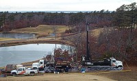 Photograph of Boart Longyear sonic drilling rig and support vehicles at a wellsite on the grounds of Ballymeade Country Club, Falmouth, MA.