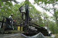 Photograph shows the sonic drill rig with the drill casing almost completely penetrated.