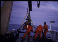 Photograph of the seismic system on deck, showing the air guns and frame, the towing weight, and the conical 
											steel trumpet that protected the wet end connection point - Thumbnail