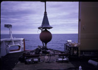Photograph of the seismic system on deck, showing the air guns and frame, the towing weight, and the conical 
											steel trumpet that protected the wet end connection point - Thumbnail