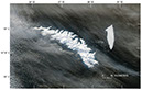 Figure 16.—MODerate-resolution Imaging Spectroradiometer (MODIS) image of South Georgia Island on 15 July 2004. The island is completely covered with snow, masking the 43 percent of the island not covered with glaciers (see fig. 17). The A-38B tabular iceberg and associated smaller icebergs can be seen east of the island. The “parent” A-38 iceberg (140 km long, 40 km wide; Ferrigno and others, 2005) calved from the Ronne Ice Shelf, East-Antarctica in early October 1998, before breaking into two tabular icebergs (A-38A and A-38B) on 22 October 1998 (Ferrigno and others, 2005). During the 6-year interval between the initial calving event and the date of this MODIS image, the A-38B iceberg has been reduced from its original dimension to about 60 km long, 15 km wide. MODIS image from the Terra satellite of the National Aeronautics and Space Administration.  NASA Terra MODIS image at http://veimages.gsfc.nasa.gov/6835/SouthGeorgia.A2004197.1635.250m.jpg. 