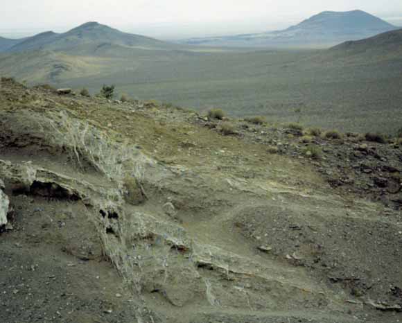 photograph of outcrop with mountains in the background