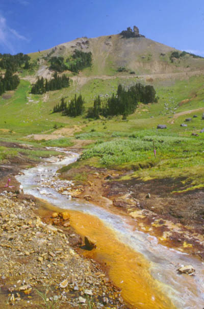 Figure 12. Aluminum and iron colloids in Daisy Creek.  View is upstream with surface-inflow site 481 on left side of stream.  Upstream of site 481, the pH of Daisy Creek is greater than about 4.5, and white aluminum colloids form.  Inflow (pH of 2.85) from site 481 decreases pH in Daisy Creek to less than 4.5, and only orange iron-oxyhydroxide colloids form. (Photograph by J.H. Lambing, U.S. Geological Survey).