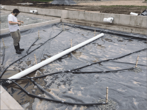 Man standing on a porous asphalt test plot surrounded by pipes an sensors.