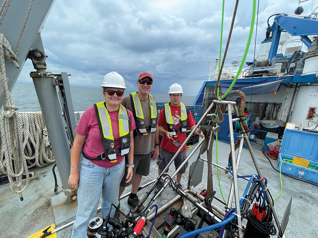 U.S. Geological Survey (USGS) scientists Chuck Worley and Seth Ackerman and USGS intern
                        Maeve Munnelly sampling sediment from the SeaBed Observation and Sampling System (SEABOSS)
                        after a deployment aboard the research vessel Connecticut in Long Island Sound, summer 2023.