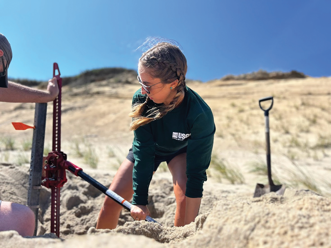 Marie Bartlett removes a fencepost used to mount a pressure sensor to measure water
                                 levels at Marconi Beach in Wellfleet, Massachusetts, during Hurricane Lee.