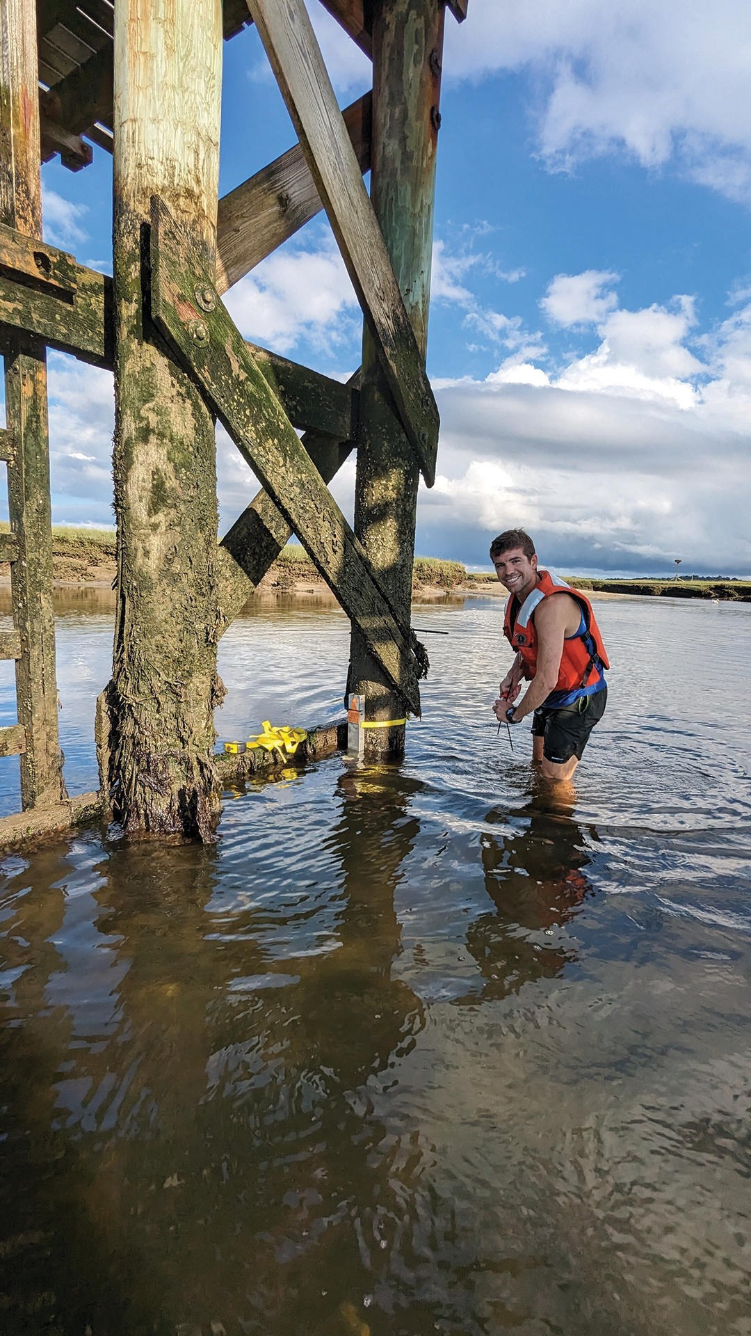 Robert Bales attaches a pressure sensor to post in the Sandwich Marsh tidal creek
                                 in Sandwich, Massachusetts, to measure the water level during Hurricane Lee.