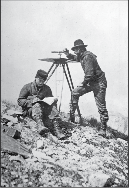 On a slight rocky slope, a man uses an alidade while another sits and records information
in an open notebook.