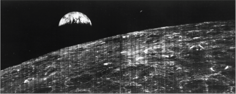 Rocky surface of Moon is visible in the foreground; the upper third of the Earth is
visible, the rest shrouded in darkness.