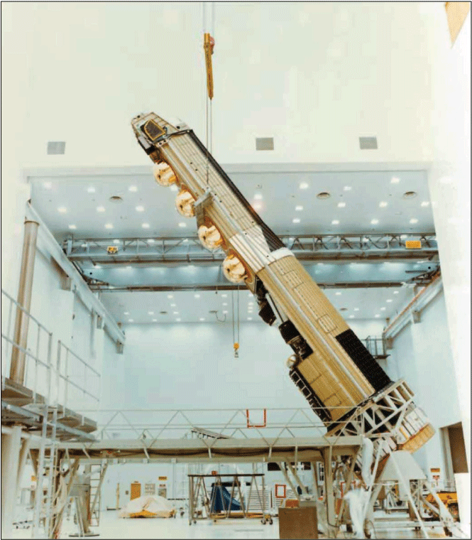 Photograph is leaning at an angle and held up by a chainfall at a bay inside a large
laboratory.