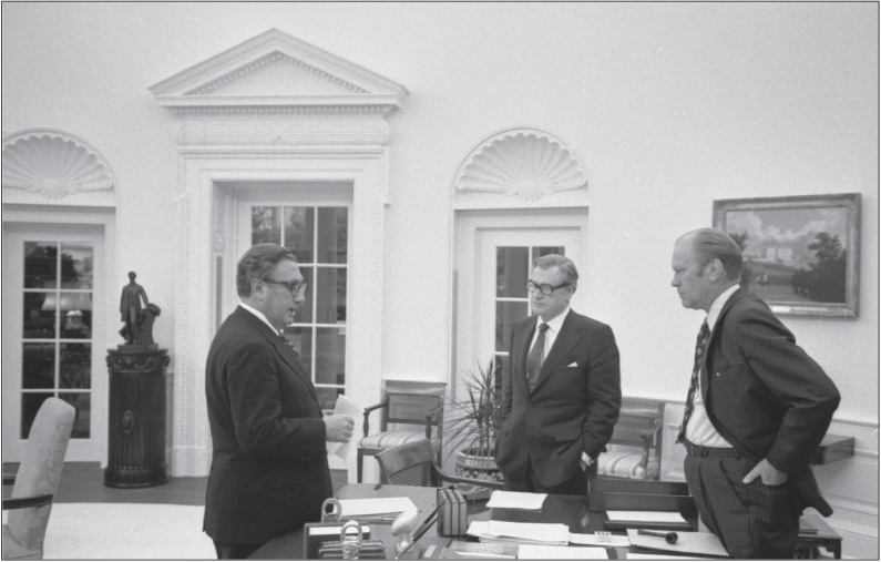 The President stands behind the desk in the Oval Office and the two men stand in front
of and beside the desk.