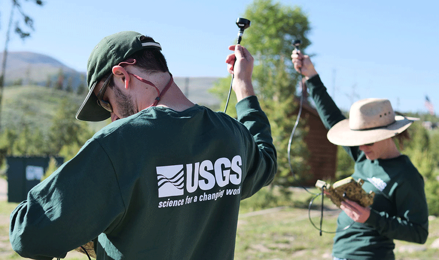 Two researchers are standing outside and holding acoustic equipment.