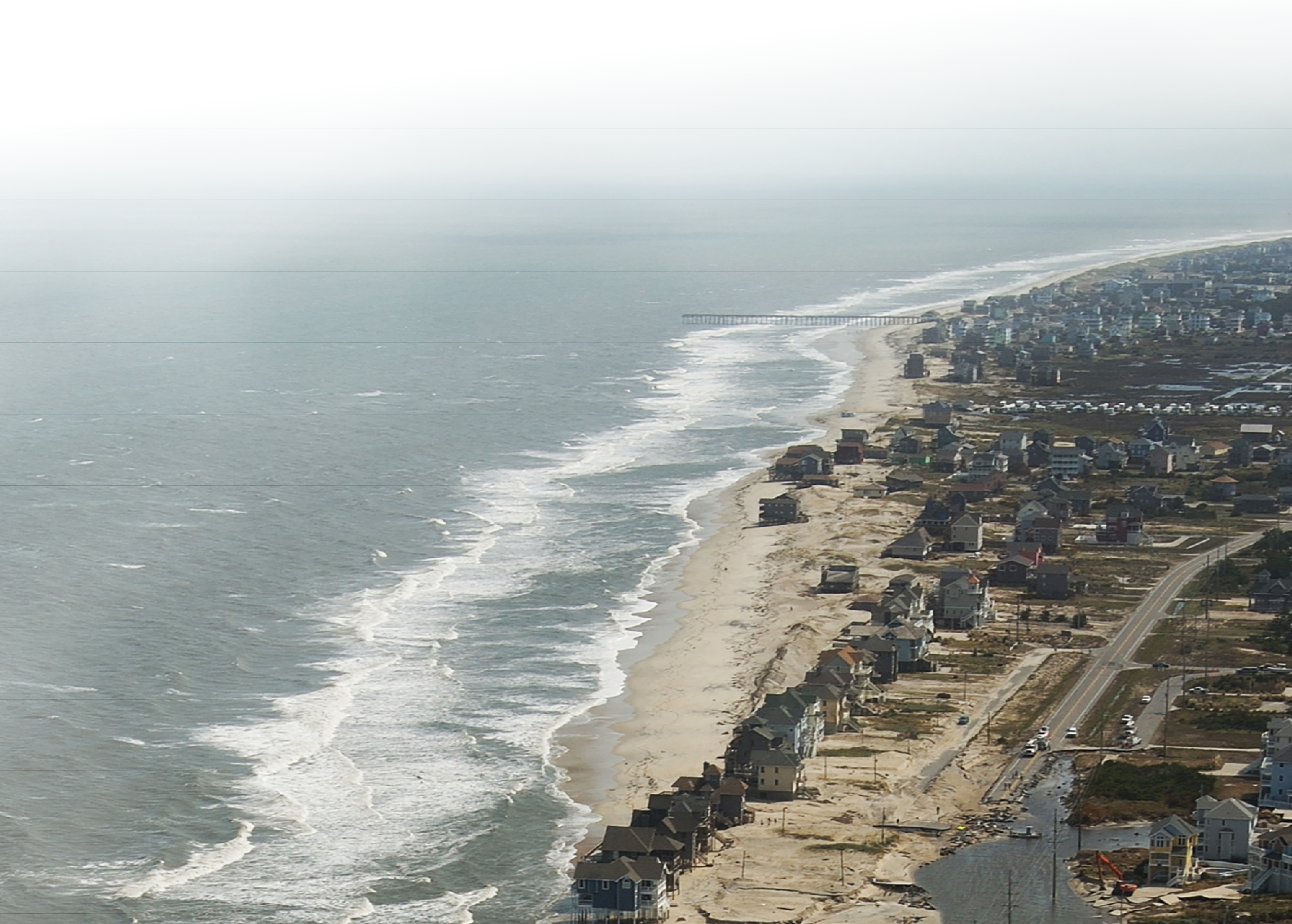 In this aerial photograph, sea water at the breach extends inland past a road, stretches
of which are destroyed.