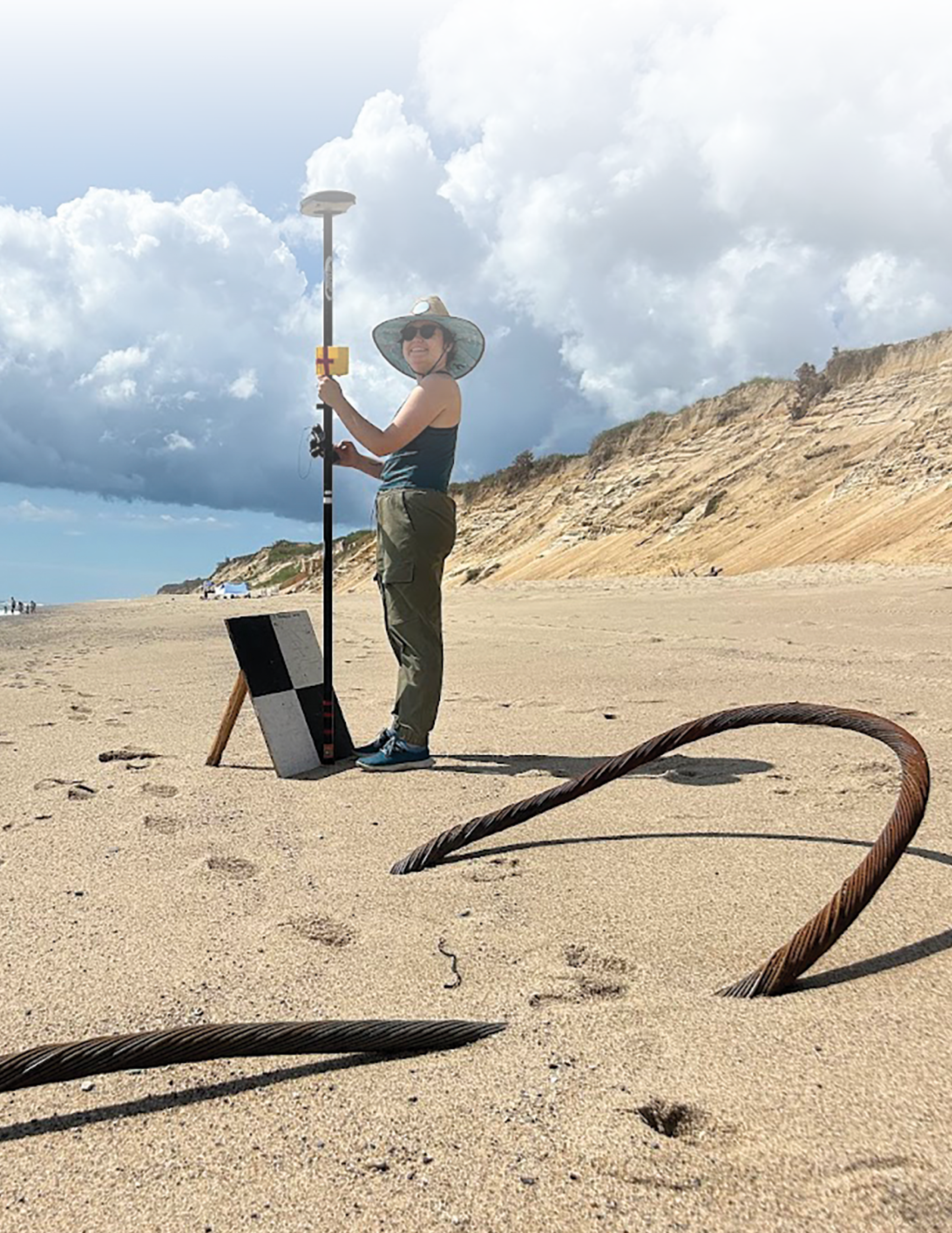 The researcher holds the base of the surveying receiver’s pole against the bottom
middle of the target. The target consists of two black and two white squares and is
propped at an angle from the sand.