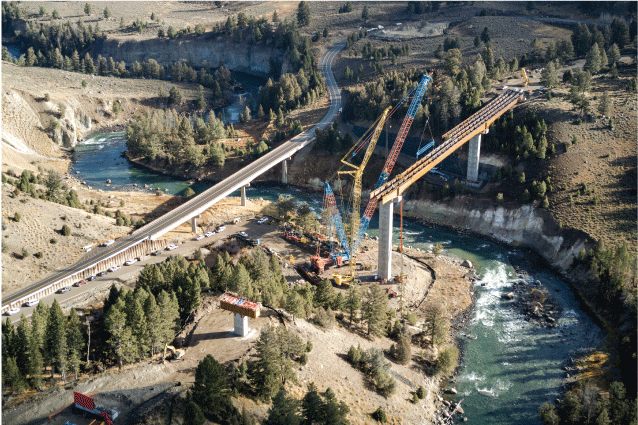 3. A construction crane is on the bank of a river as it winds through a vegetated
landscape, and a bridge is being built across the river.