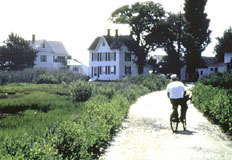 Picture of a man riding his bike towards a small town.