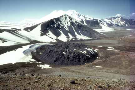 Photograph of dark lava dome with snow on one side
