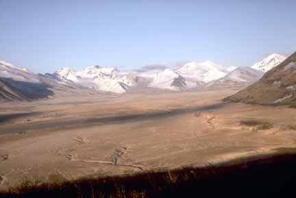 Photograph in flatter lighting of ash flow in foreground and snow-covered mountains in background