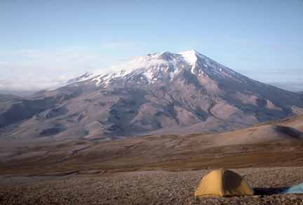Photograph of snow-capped volcano in background; backpacking tent in foreground