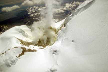 Photograph from air of sulfur-stained (yellow) snow and rocks around steaming vent