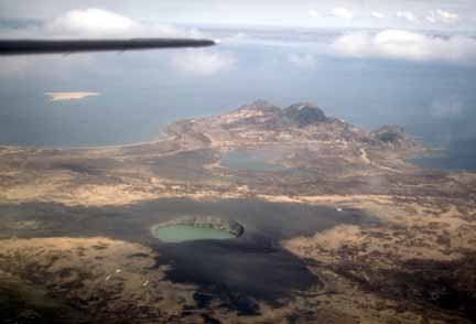 Photograph from air of flatland with lake-filled volcanic crater in middleground