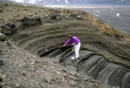 Photograph of scientist with shovel sampling tephra