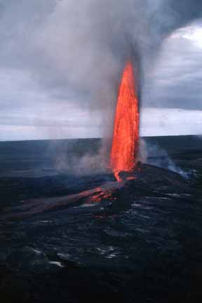 photo 018.  Low-elevation oblique aerial photo of tall, narrow vertical spout of red-hot lava