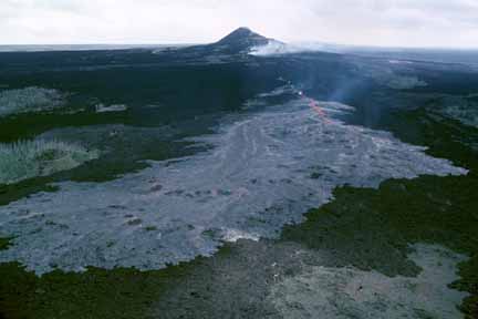 photo 033.  Photo of smoking gray somewhat-cooled lava flow with small volcano in background