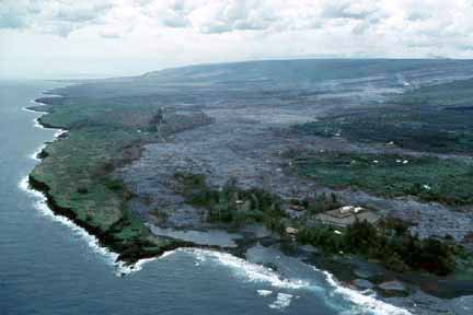 photo 068.  Low-elevation oblique aerial photo of lava flow nearing lagoon and ocean; houses nearly all burned up as lava reaches the sea