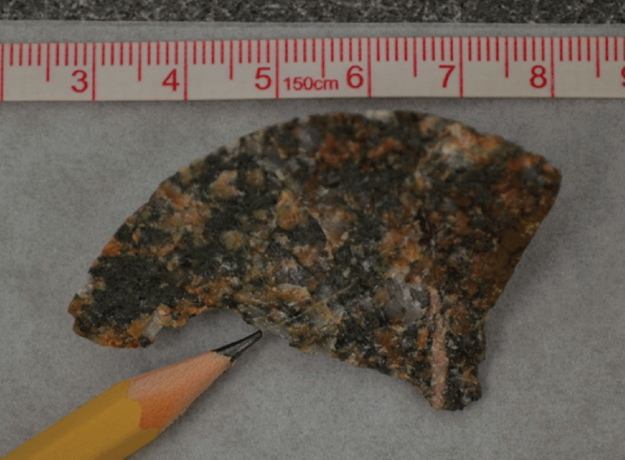 A rock core chip is shown next to a pencil and ruler for scale.