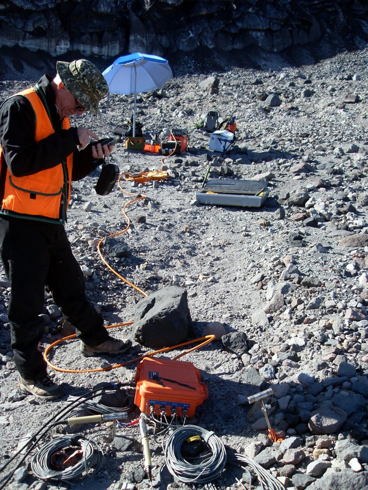 The first author with the Stratagem EH-4 controlled-source audio-frequency magnetotelluric (CSAMT) receiver and the electrodes used for the electrical-field measurements. The location here is station MSH-1001-1002, just north of Crater Glacier (seen in the background behind the umbrella). 
