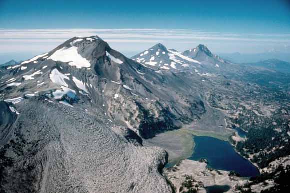 [Aerial view towards north of the Three Sisters volcanoes in Oregon. Left to right, South Sister, Middle Sister, and North Sister. (Photograph by Lyn Topinka, September 1985.)]