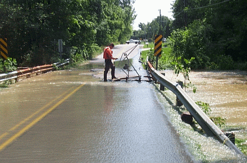 Kokomo Creek flows over the bridge in the town of Kokomo, Indiana, as a U.S. Geological Survey streamgager prepares to make a discharge measurement.