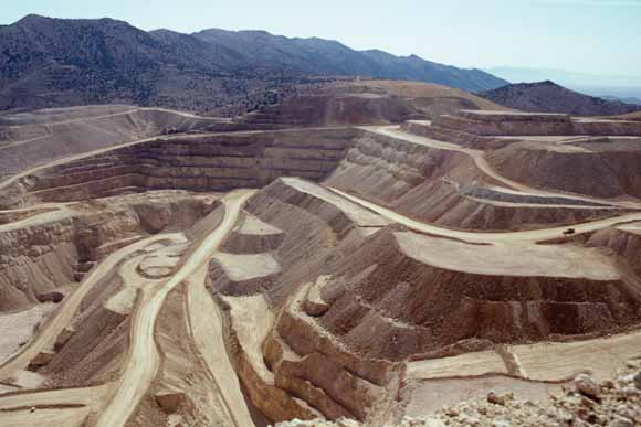 photograph of large open-pit mine showing terraces, roads, and an ant-looking speck that turns out to be a large truck