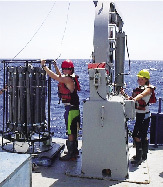 Photograph of two scientists at work on platform over ocean waters