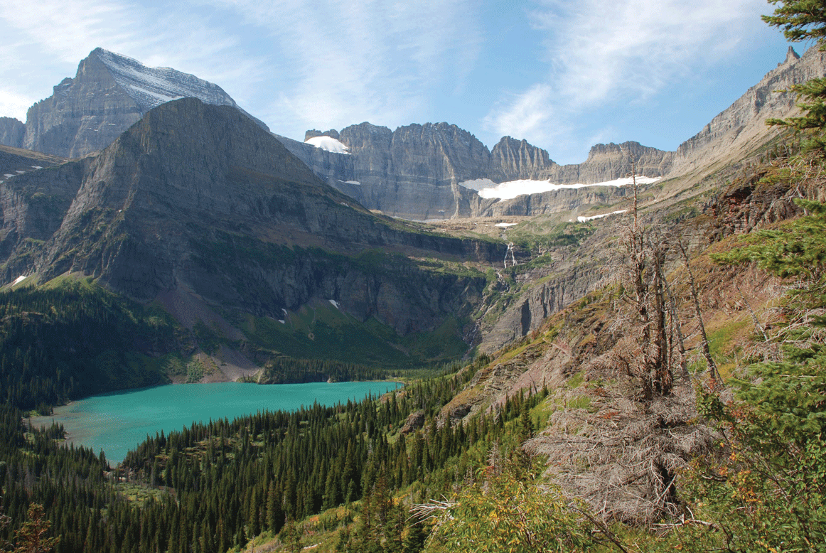 Photograph of Grinnell Glacier shows a mostly rocky surface with little snow and ice
                     cover and a stream of water below.