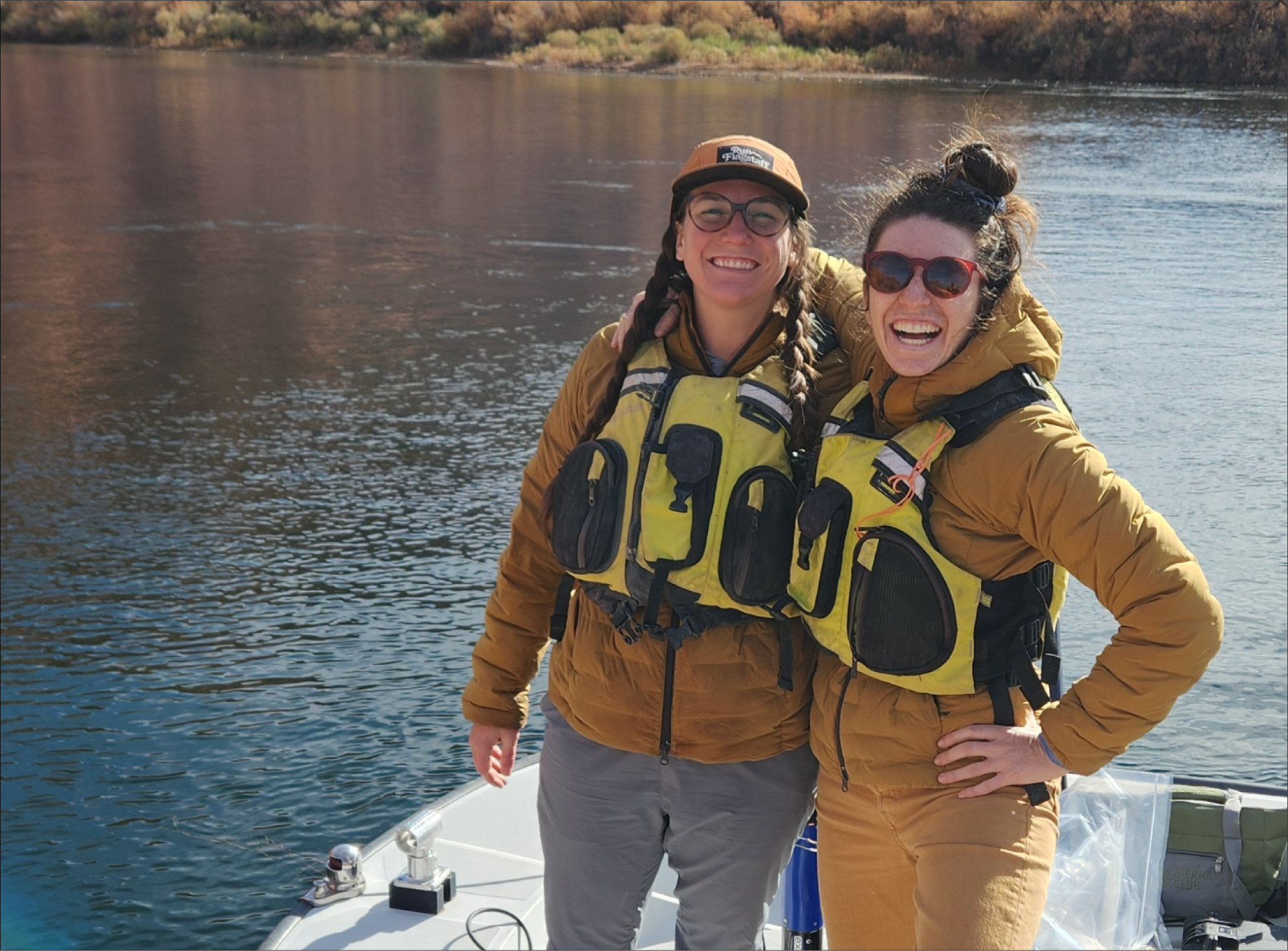 U.S. Geological Survey technicians wearing personal flotation devices pose happily
                     near the shore of the Colorado River at Lees Ferry.