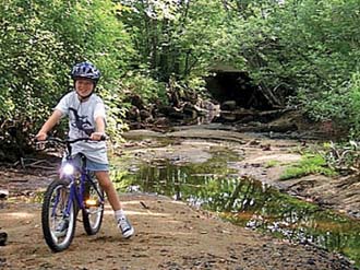 Photo of boy riding a bicycle on what would normally be the Ipswich River stream bottom