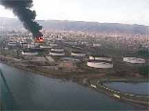 photo of giant oil tank in flames with dozens of others around it